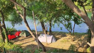 Eine Gruppe von Zelten im Schatten von Bäumen in der Nähe des Wassers in der Unterkunft Auto kamp Hacienda Kolenda in Mostar