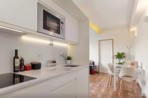 a white kitchen with a counter and a dining room at Studios Baixa Downtown Porto in Porto