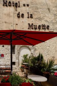 a hotel de la muerte sign on a building with a red umbrella at Hôtel La Muette in Arles