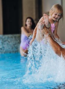 a young girl playing in the water in a pool at Gabija Hotel SPA & Conferences in Palanga
