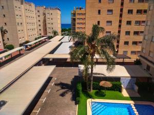 an overhead view of a building with a pool and palm trees at Chula Vista Apartamento, 200m de la playa, piscina, parking in Daimuz