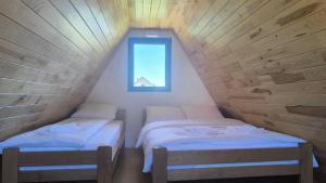 deux lits dans une petite pièce avec une fenêtre dans l'établissement Apartmani Stara kuca, à Žabljak
