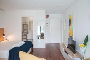 a living room with a bed and a television at Sunflower Luxury Loft w AC Downtown and Metro in Porto