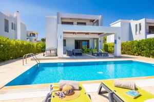 a villa with a swimming pool in front of a house at Villa Tsampikos in Lachania