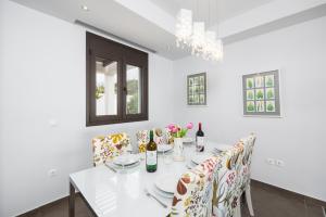 a white dining room with a white table and chairs at Villa Tsampikos in Lachania