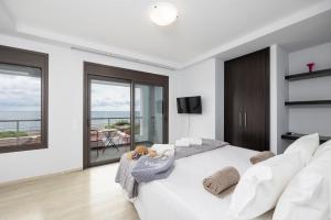 a white bedroom with a large bed and a balcony at Villa Tsampikos in Lachania +33 photos