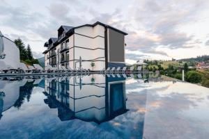 a building with its reflection in a pool of water at Milana SPA & Hotel - SPA included in Bukovel
