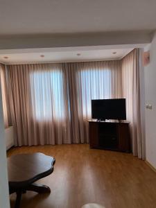 a living room with a flat screen tv and a table at ХОТЕЛ ВИЛА Мая in Pleven