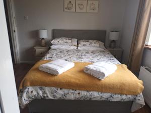 a bedroom with a bed with towels on it at Drumgauty Cottage in Strabane