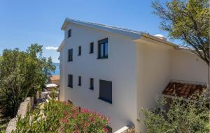 a white building with trees in the foreground at Beautiful Apartment In Novi Vinodolski in Novi Vinodolski
