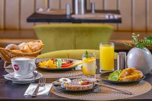 a table with plates of breakfast food and orange juice at Andrassy Thai Hotel in Budapest