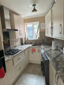 eine Küche mit weißen Schränken und Granitarbeitsflächen in der Unterkunft Lavish 3 story house with full of comfort in Dagenham + 17 Fotos