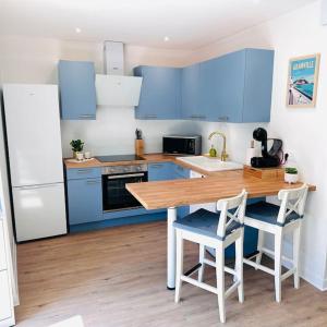 a kitchen with blue cabinets and a wooden table and chairs at Appartement Au Cœur de Granville in Granville