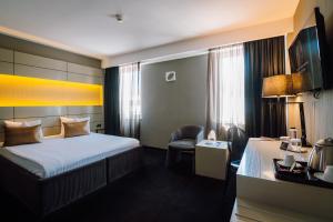 a hotel room with a bed and a chair at Plaza V Hotel in Târgu-Mureş +75 photos