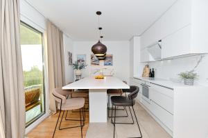 a white kitchen with a white table and chairs at Sea Whisper apartment Zadar in Zadar