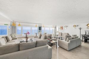 a living room with couches and tables and windows at Hotel La Perla Del Capo in Ospedaletti