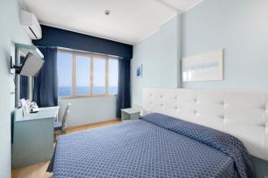 a bedroom with a blue and white bed and a desk at Hotel La Perla Del Capo in Ospedaletti