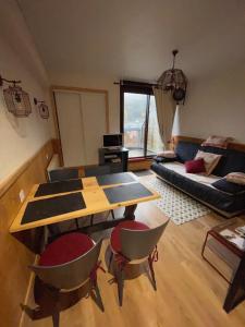 a living room with a table and chairs and a couch at Appartements bien situés avec terrasse in Le Mont-Dore