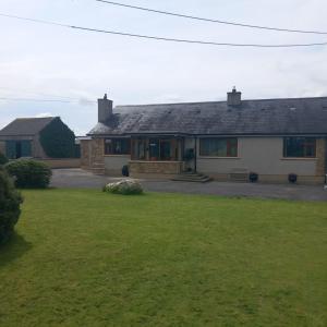 une maison avec une pelouse verte devant dans l'établissement Drumgauty Cottage, à Strabane