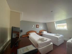 a hotel room with two beds and a desk at The Beach Hotel in Brighton & Hove