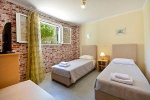 a bedroom with two beds and a brick wall at Calm & Peaceful in Gouvia