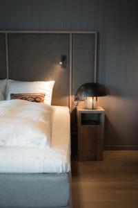 a bedroom with a bed and a lamp on a night stand at Henningsv&aelig;r Bryggehotell - by Classic Norway Hotels in Henningsv&aelig;r