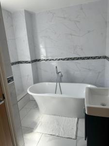 ein weißes Badezimmer mit Badewanne und Waschbecken in der Unterkunft Lavish 3 story house with full of comfort in Dagenham
