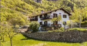 Casa blanca con una pared de piedra y árboles en B&B Haus Senter, en Trambileno