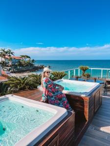 une femme debout à côté d'un bain à remous sur un balcon dans l'établissement Pousada Gaúcha, à Bombinhas