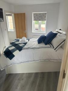 ein weißes Bett mit blauen Kissen im Schlafzimmer in der Unterkunft Lavish 3 story house with full of comfort in Dagenham