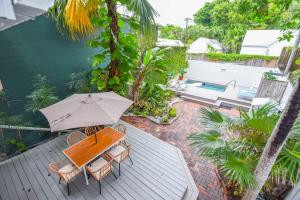 キーウェストにあるNew Rose Retreat - Pool & Parkingのテーブルと椅子と傘のあるパティオ