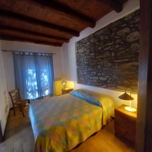 a bedroom with a bed and a stone wall at Agriturismo Rio Lunei in Stella