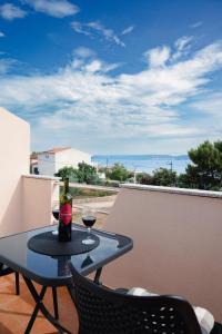 a table with two glasses of wine on a balcony at Apartmani Natalija 4 Stars in Mrljane