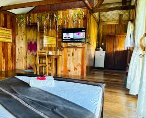 a room with a bed and a tv in it at White Beach Front and Cottages in Buruanga