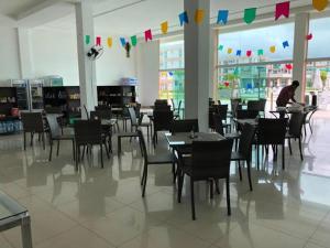 a restaurant with tables and chairs and a person in the background at Muro alto condomínio clube in Ipojuca
