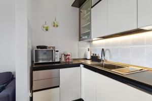 a kitchen with white cabinets and a sink and a microwave at NAT Apartments in Koper +8 photos