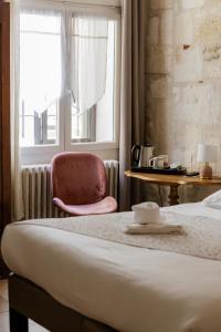 a bedroom with a bed and a chair and a window at Hôtel La Muette in Arles