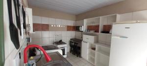 a small kitchen with white cabinets and a refrigerator at Casa temporada Araçoiaba in Araçoiaba +37 photos