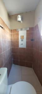 a bathroom with a toilet and a shower with brown tiles at Casa temporada Araçoiaba in Araçoiaba