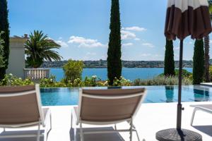 una piscina con due sedie e un ombrellone di Villa Silvia Apartments a San Felice del Benaco