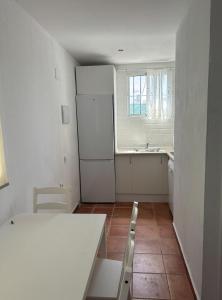 a kitchen with a table and a white refrigerator at Villa con piscina in Chiclana de la Frontera +5 photos