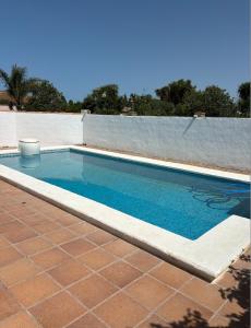 a swimming pool with a tiled floor and a brick patio at Villa con piscina in Chiclana de la Frontera