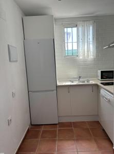 a kitchen with a white refrigerator and a sink at Villa con piscina in Chiclana de la Frontera