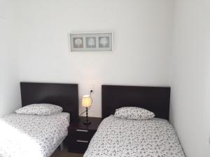 two beds in a room with white walls at Apartamentos Panticosa in Panticosa