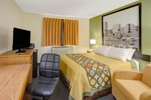 ein kleines Hotelzimmer mit einem Bett und einem Stuhl in der Unterkunft Super 8 by Wyndham College Park Wash DC Area in College Park
