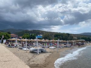 a beach with umbrellas and people sitting on the sand at Yaya house in Skala Sotiros