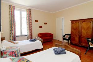 um quarto de hotel com duas camas e uma cadeira vermelha em Les Volets Bleus em Sallèles-dʼAude