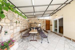 een patio met een tafel en stoelen en een stenen muur bij Apartment Marta in Maslenica