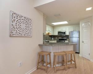 a kitchen with a counter with stools and a refrigerator at Phoenix X 212 condo in Orange Beach