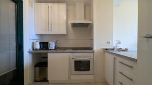 eine kleine Küche mit weißen Schränken und einem Herd in der Unterkunft LOS ALTOS sea view apartment in Finestrat